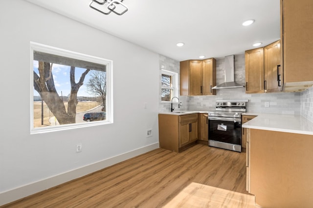 kitchen with sink, light hardwood / wood-style flooring, backsplash, wall chimney exhaust hood, and stainless steel electric range