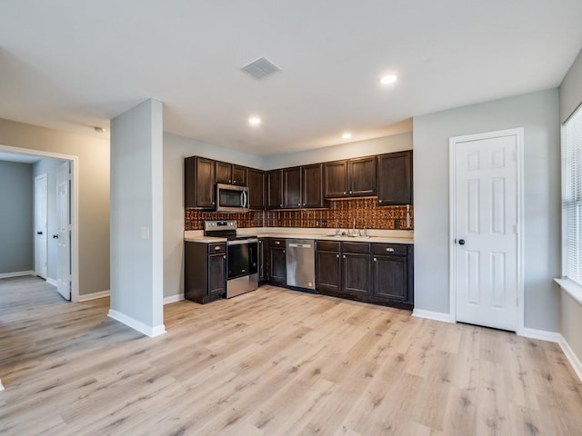 kitchen with backsplash, dark brown cabinets, light hardwood / wood-style flooring, and appliances with stainless steel finishes