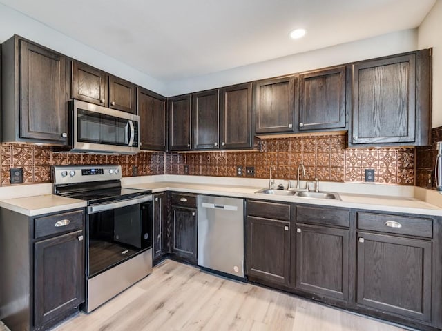 kitchen with dark brown cabinetry, sink, tasteful backsplash, light wood-type flooring, and stainless steel appliances