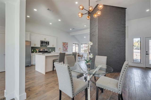 dining space featuring hardwood / wood-style flooring, plenty of natural light, sink, and an inviting chandelier