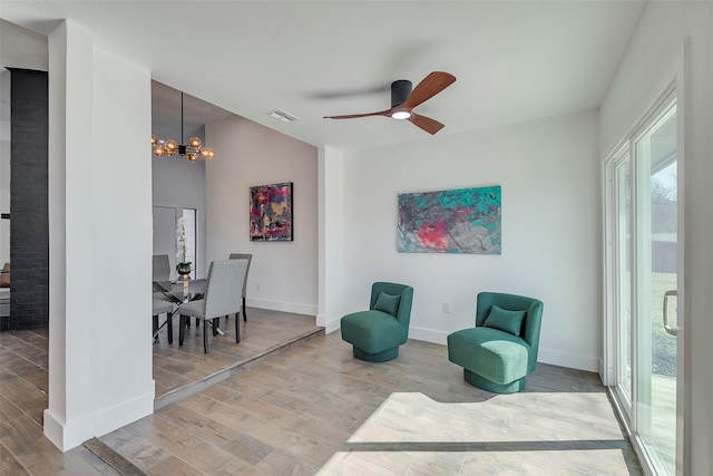 living area featuring ceiling fan with notable chandelier and hardwood / wood-style floors