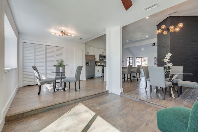 dining area with lofted ceiling and ceiling fan with notable chandelier