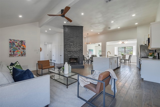 living room with a fireplace, lofted ceiling with beams, sink, dark hardwood / wood-style flooring, and ceiling fan