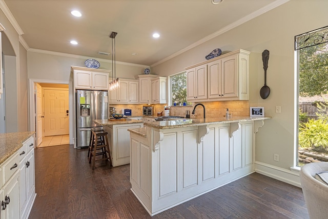 kitchen featuring light stone counters, decorative light fixtures, a kitchen breakfast bar, and stainless steel refrigerator with ice dispenser