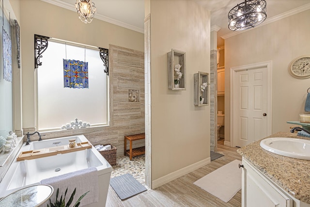 bathroom with toilet, a chandelier, ornamental molding, vanity, and a relaxing tiled tub