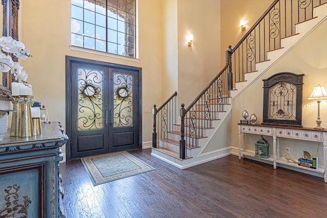 entryway with a towering ceiling, dark hardwood / wood-style floors, and french doors