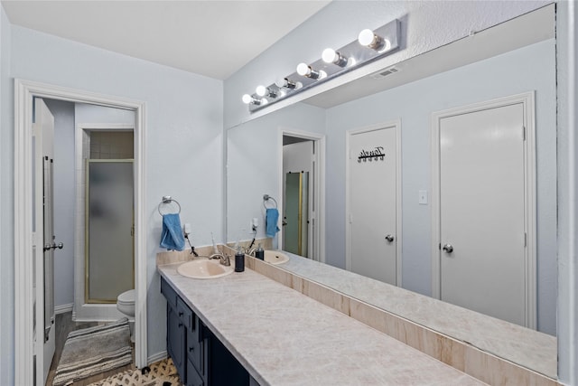 bathroom featuring vanity, a shower with door, and toilet