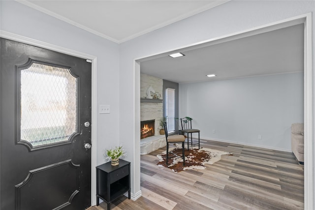 foyer entrance with hardwood / wood-style flooring, a fireplace, ornamental molding, and a healthy amount of sunlight