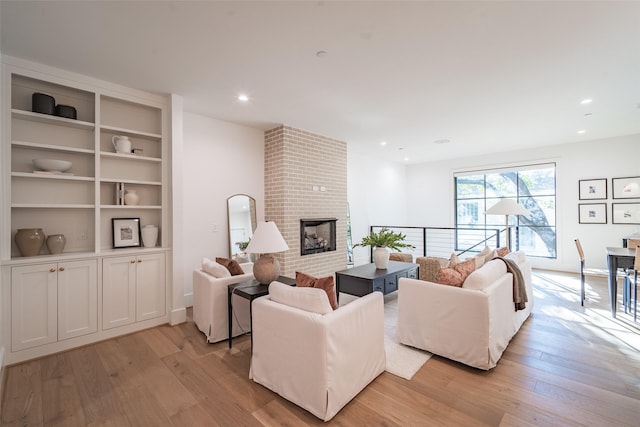 living room featuring a brick fireplace and light hardwood / wood-style floors