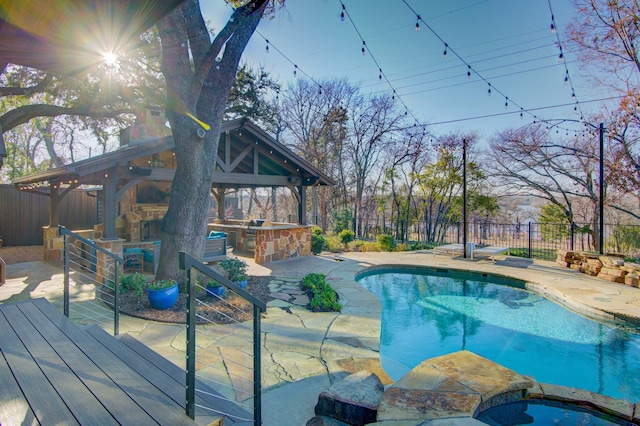 view of swimming pool featuring a gazebo, a patio, an outdoor stone fireplace, and a bar