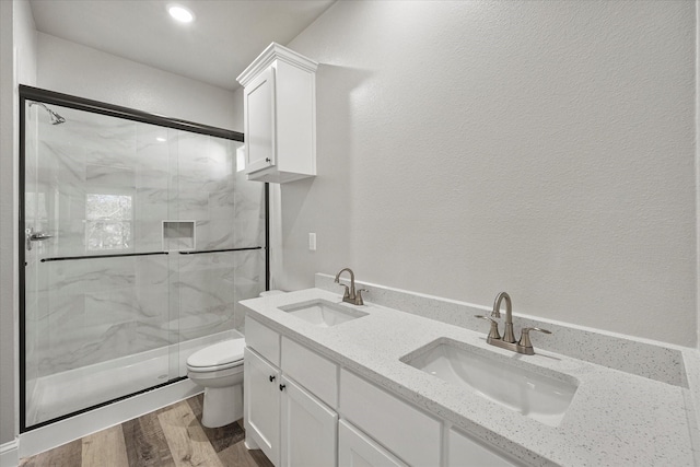 bathroom with walk in shower, vanity, toilet, and wood-type flooring