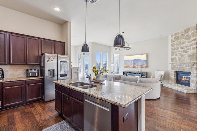 kitchen featuring sink, tasteful backsplash, hanging light fixtures, a center island with sink, and appliances with stainless steel finishes