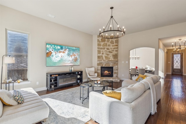 living room with dark hardwood / wood-style flooring, an inviting chandelier, and a fireplace