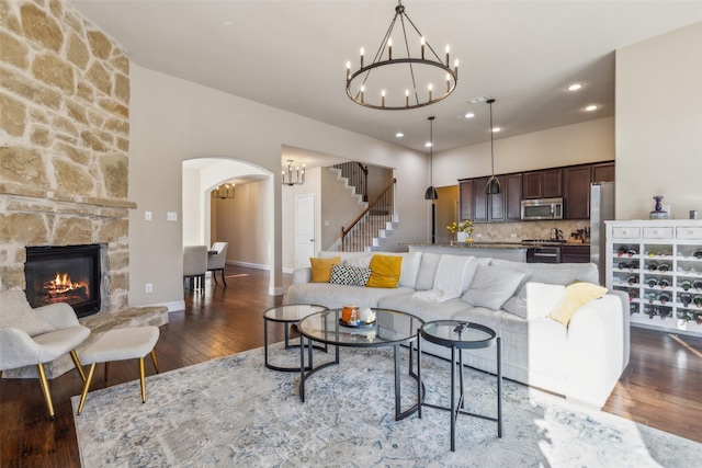 living room featuring dark hardwood / wood-style floors, a stone fireplace, and a notable chandelier