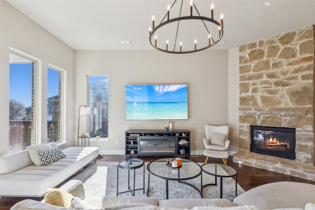 living room featuring hardwood / wood-style flooring, a stone fireplace, and a wealth of natural light