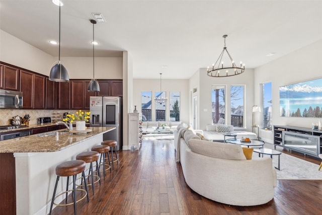 living room featuring sink, dark wood-type flooring, and an inviting chandelier