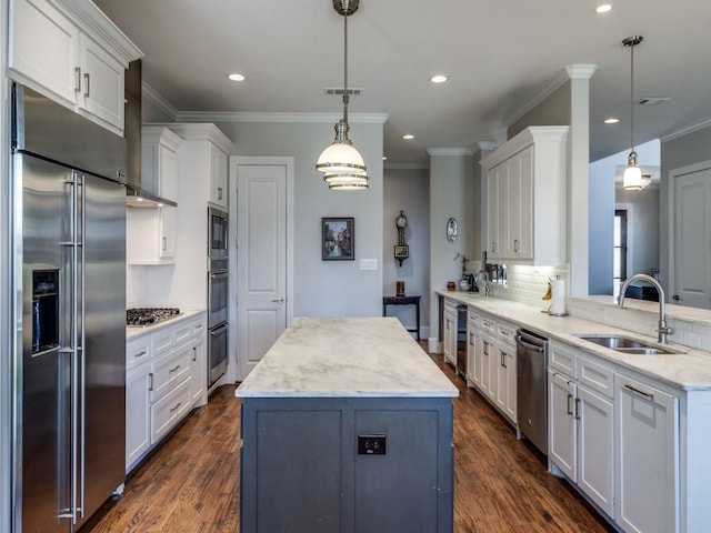 kitchen featuring pendant lighting, white cabinetry, built in appliances, and sink