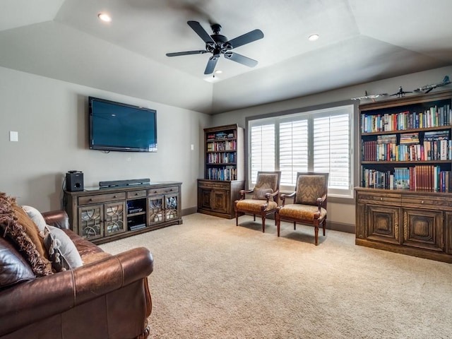 living room with a raised ceiling, lofted ceiling, light colored carpet, and ceiling fan