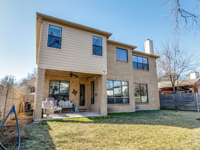 rear view of house featuring ceiling fan, an outdoor living space, a patio, and a lawn