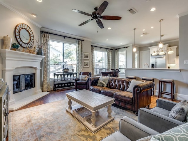 living room with wood-type flooring, ornamental molding, and ceiling fan