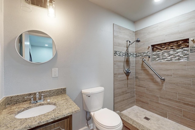 bathroom featuring vanity, a tile shower, and toilet