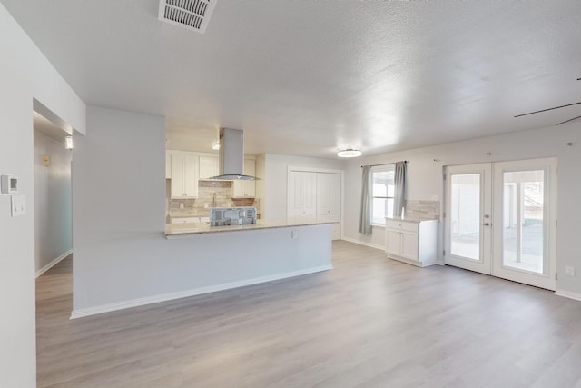 unfurnished living room featuring a textured ceiling, light wood-type flooring, and french doors