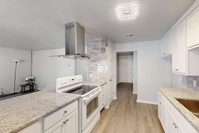 kitchen with white electric range, range hood, white cabinets, light stone countertops, and light wood-type flooring