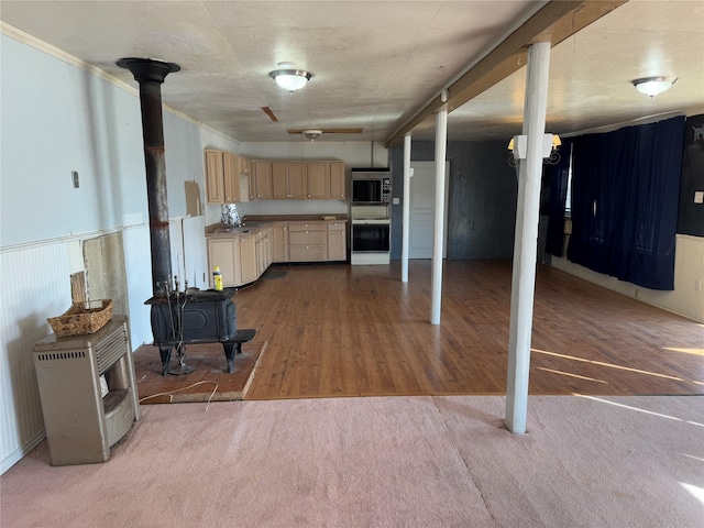 kitchen with light colored carpet, light brown cabinetry, light wood-style floors, ornamental molding, and a wood stove