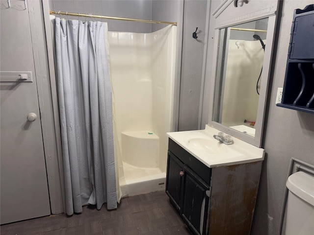 full bath featuring toilet, a stall shower, and vanity