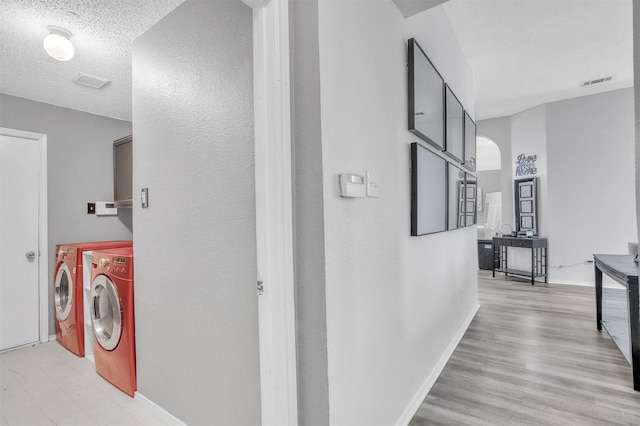 corridor with separate washer and dryer and a textured ceiling