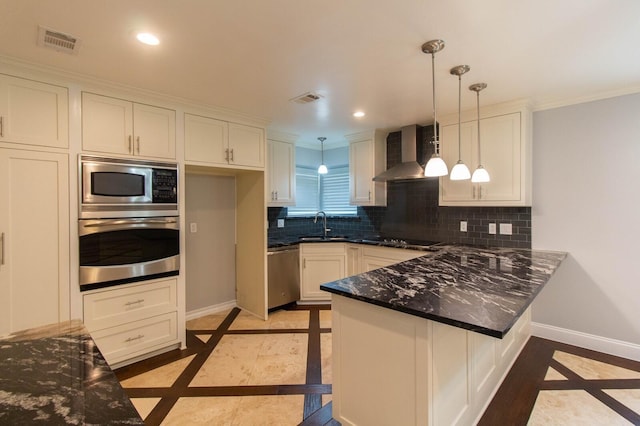 kitchen featuring white cabinets, hanging light fixtures, kitchen peninsula, stainless steel appliances, and wall chimney range hood