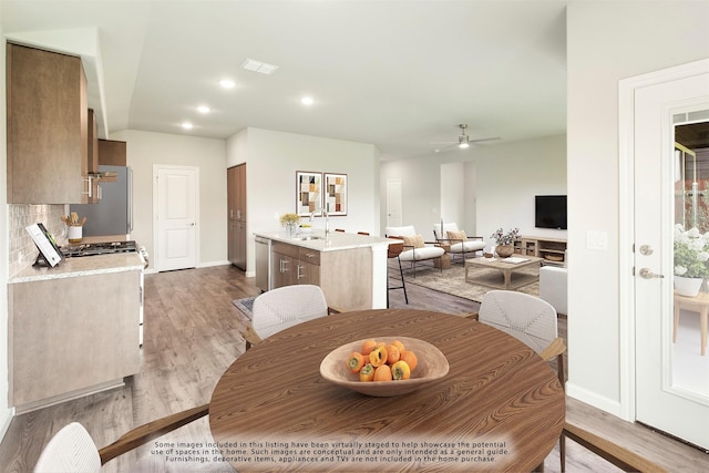 dining space with ceiling fan, sink, and light hardwood / wood-style flooring