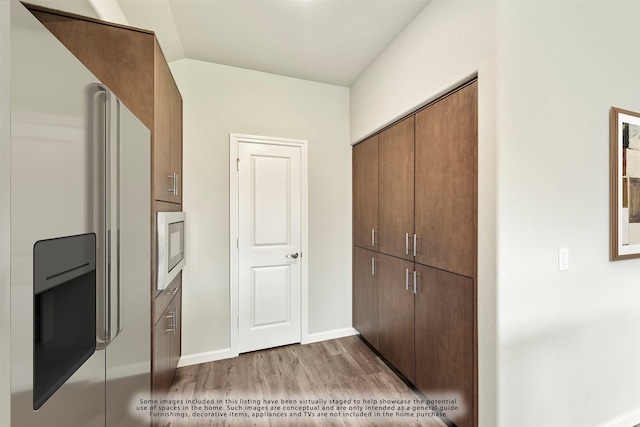 kitchen with built in microwave, stainless steel fridge, and light wood-type flooring