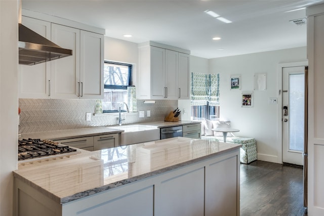 kitchen with sink, appliances with stainless steel finishes, range hood, light stone countertops, and white cabinets