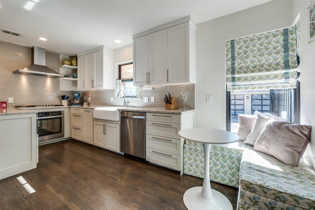 kitchen featuring wall chimney exhaust hood, stainless steel appliances, sink, and white cabinets