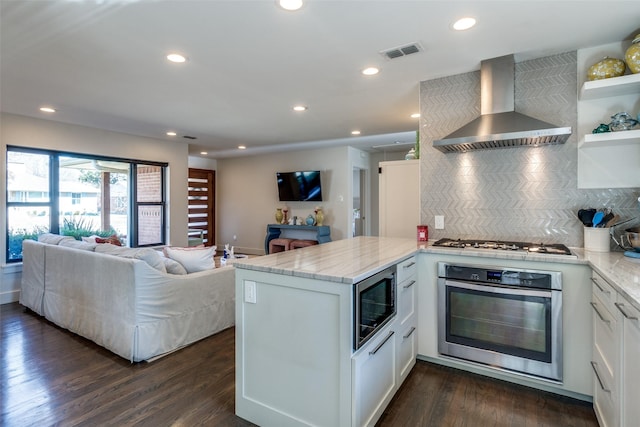 kitchen featuring wall chimney exhaust hood, stainless steel appliances, kitchen peninsula, and white cabinets