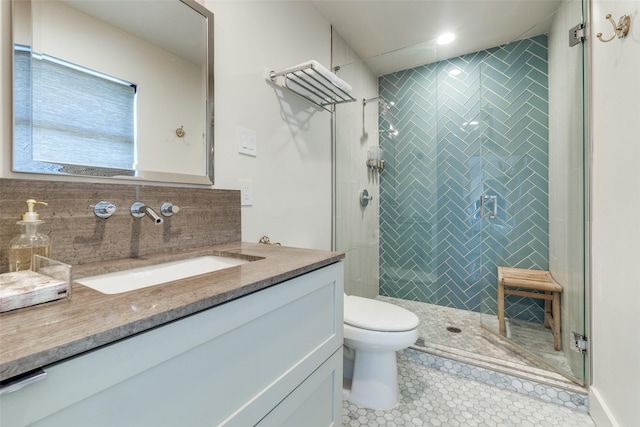 bathroom featuring vanity, backsplash, a shower with door, and toilet