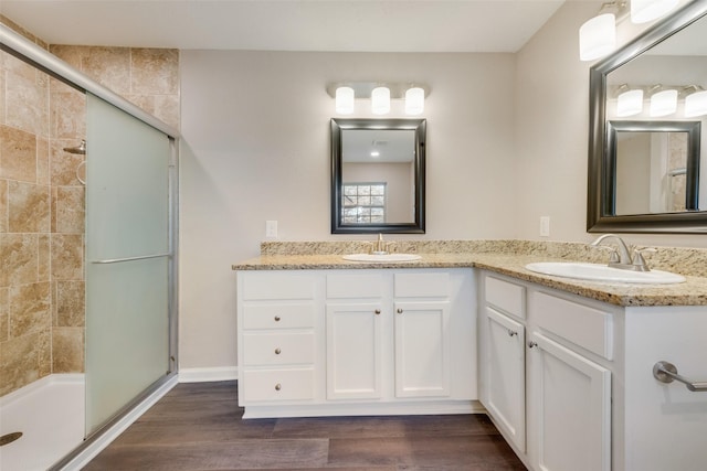 bathroom featuring wood-type flooring, a shower with door, and vanity