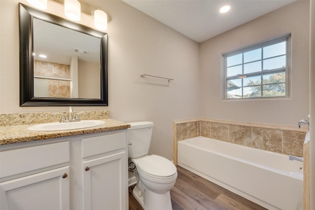 bathroom featuring vanity, hardwood / wood-style floors, toilet, and a bathing tub