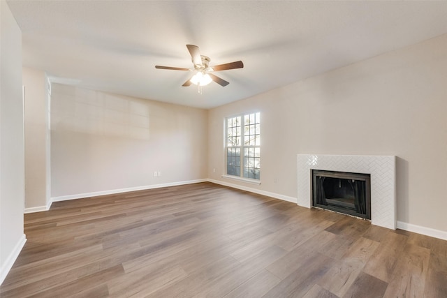 unfurnished living room featuring ceiling fan, a fireplace, and wood-type flooring