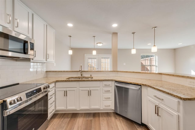 kitchen featuring white cabinetry, sink, hanging light fixtures, kitchen peninsula, and stainless steel appliances