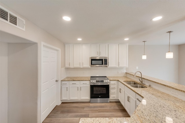 kitchen featuring decorative light fixtures, white cabinetry, sink, kitchen peninsula, and stainless steel appliances