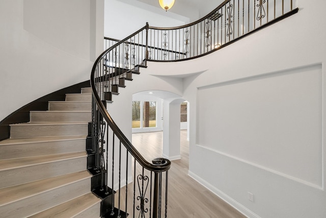 staircase featuring hardwood / wood-style floors and a high ceiling