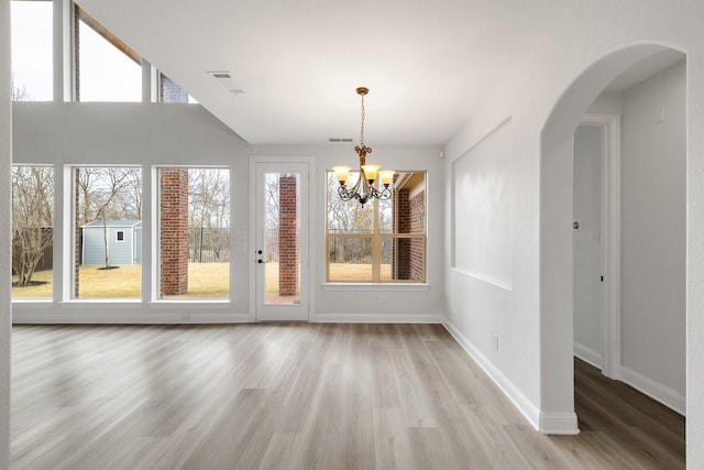 unfurnished dining area with an inviting chandelier and light hardwood / wood-style flooring