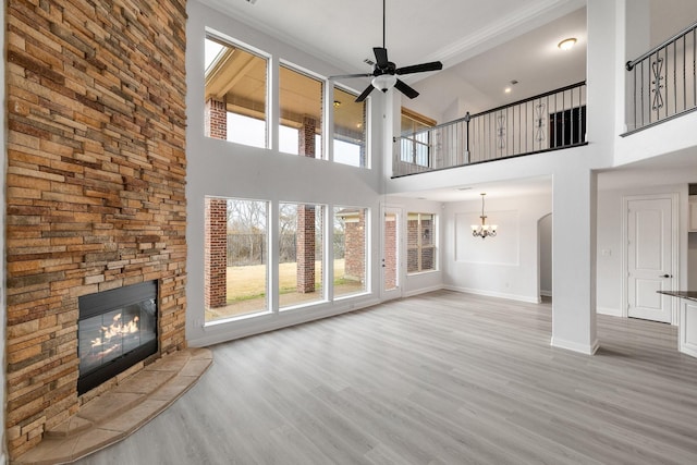 unfurnished living room featuring hardwood / wood-style flooring, a fireplace, and ceiling fan with notable chandelier