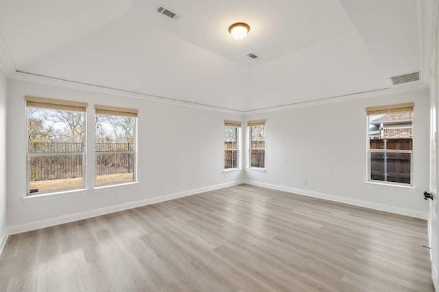 empty room with vaulted ceiling, plenty of natural light, and light hardwood / wood-style flooring