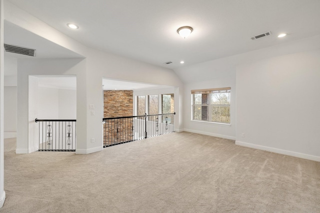 spare room featuring lofted ceiling and light carpet