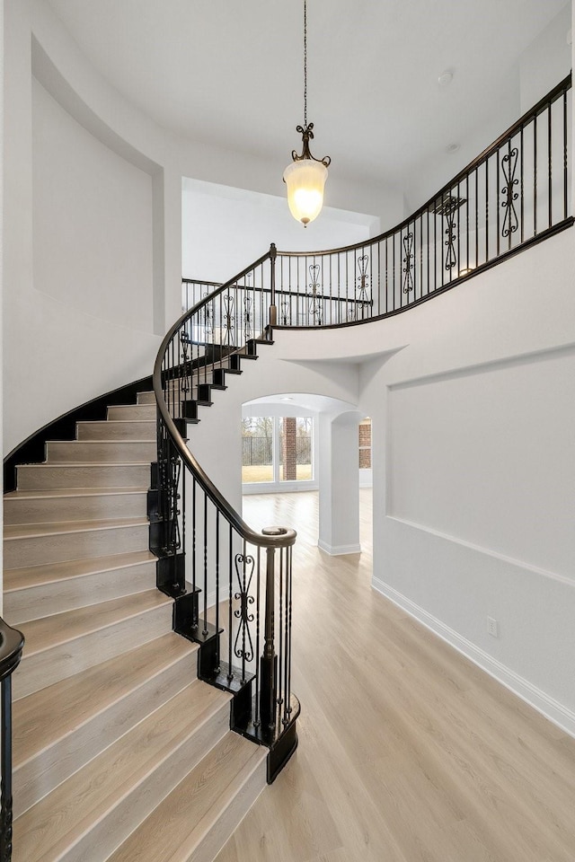 stairway with a towering ceiling and hardwood / wood-style floors