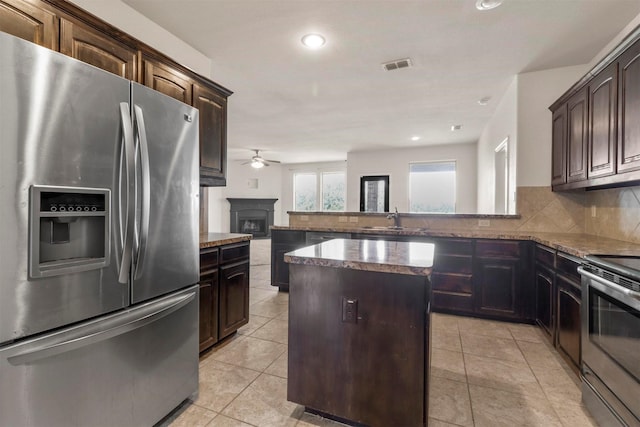 kitchen featuring dark brown cabinetry, sink, a center island, stainless steel appliances, and decorative backsplash