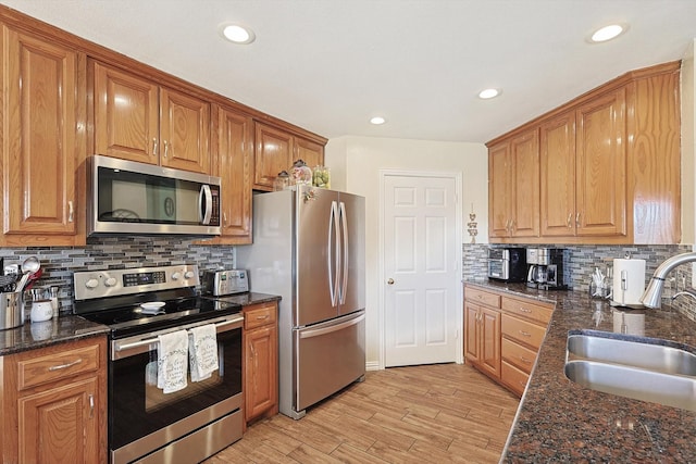 kitchen with appliances with stainless steel finishes, sink, dark stone counters, and backsplash